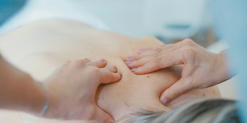 person massaging the back of a woman